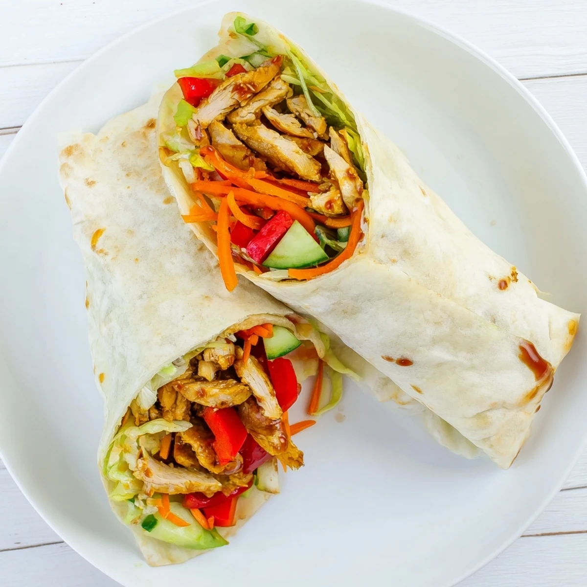 Fresh lettuce and colorful bell peppers layered inside sweet chili chicken wraps with tangy sauce
