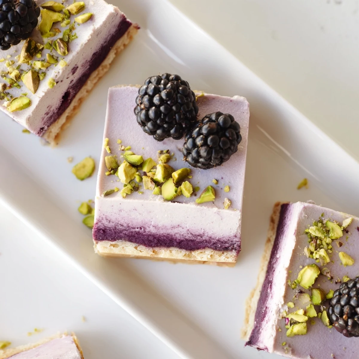 Sliced Blackberry Pistachio Dream Bars featuring green nutty crust topped with vibrant purple blackberry swirl