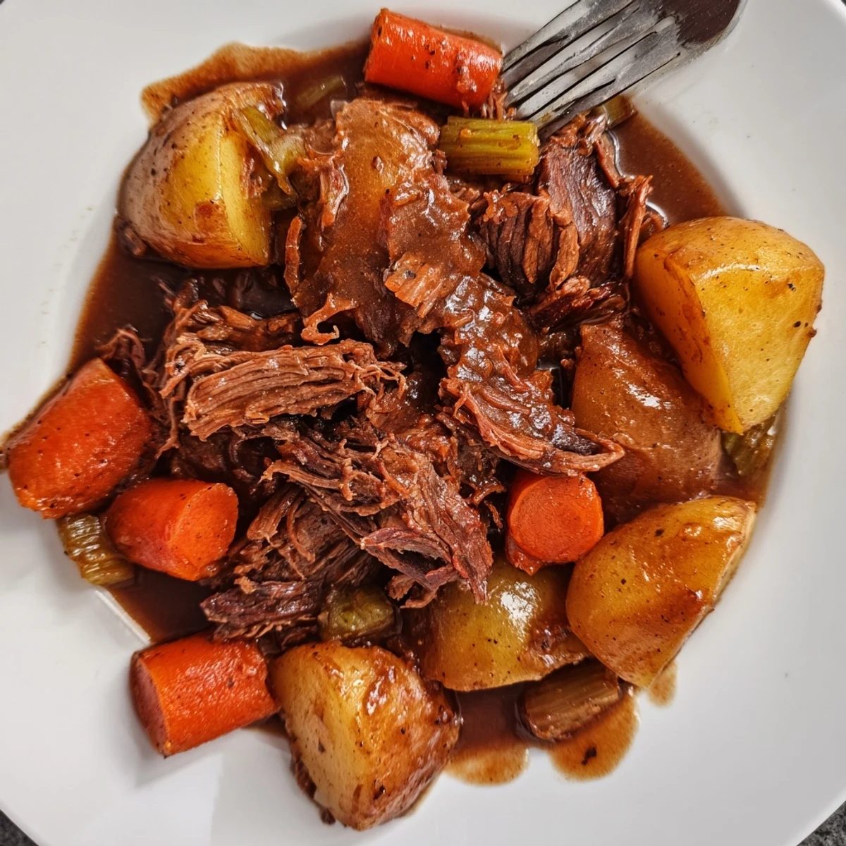 Golden brown Southern style pot roast with tender carrots and potatoes in rich savory gravy