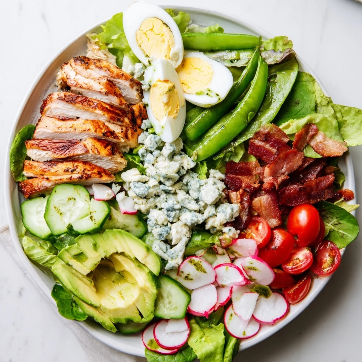 Vibrant Spring Cobb Salad with snap peas, tomatoes, avocado slices, and grilled chicken topped with tangy herb dressing