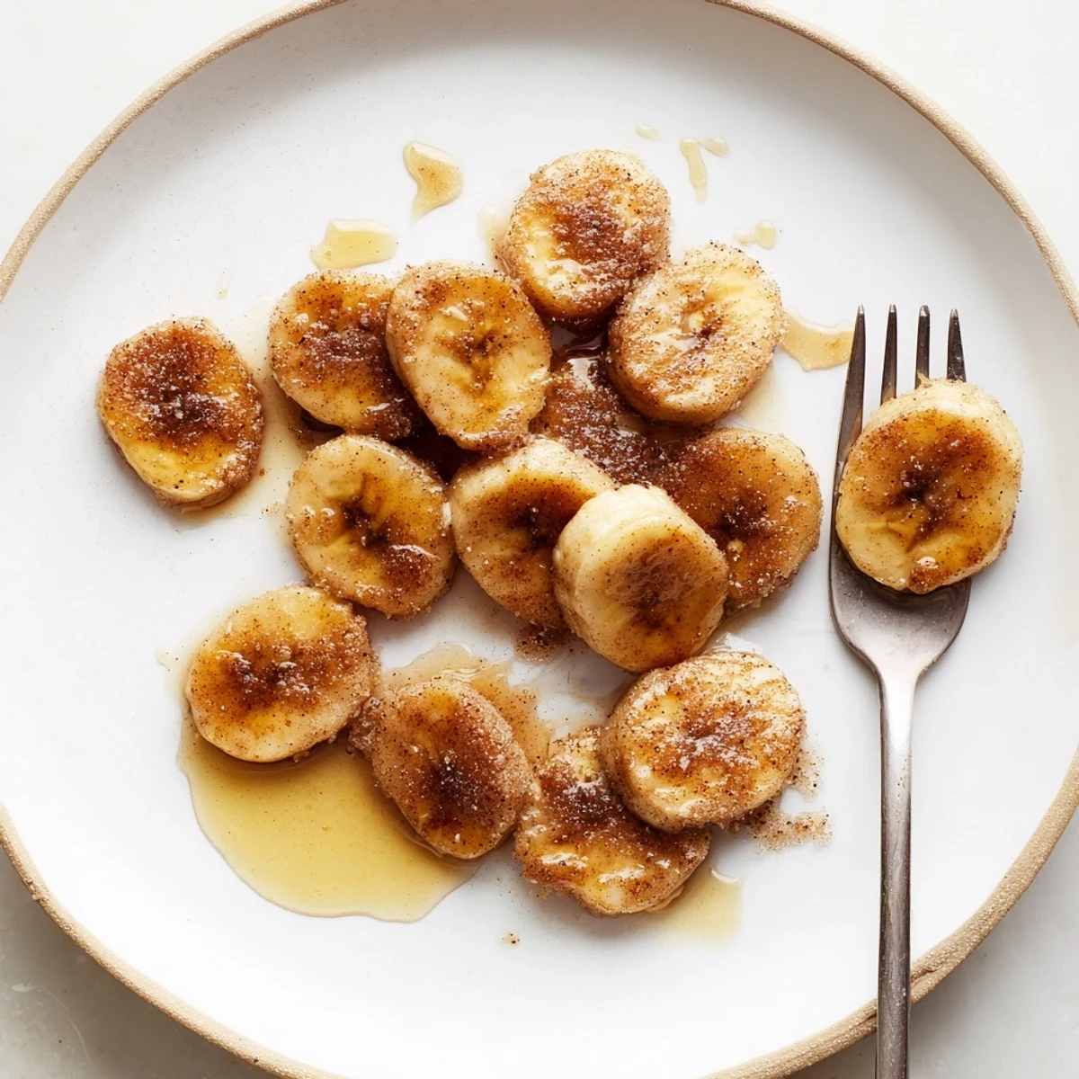 Sweet pan fried cinnamon bananas sizzling in skillet with cinnamon sugar coating