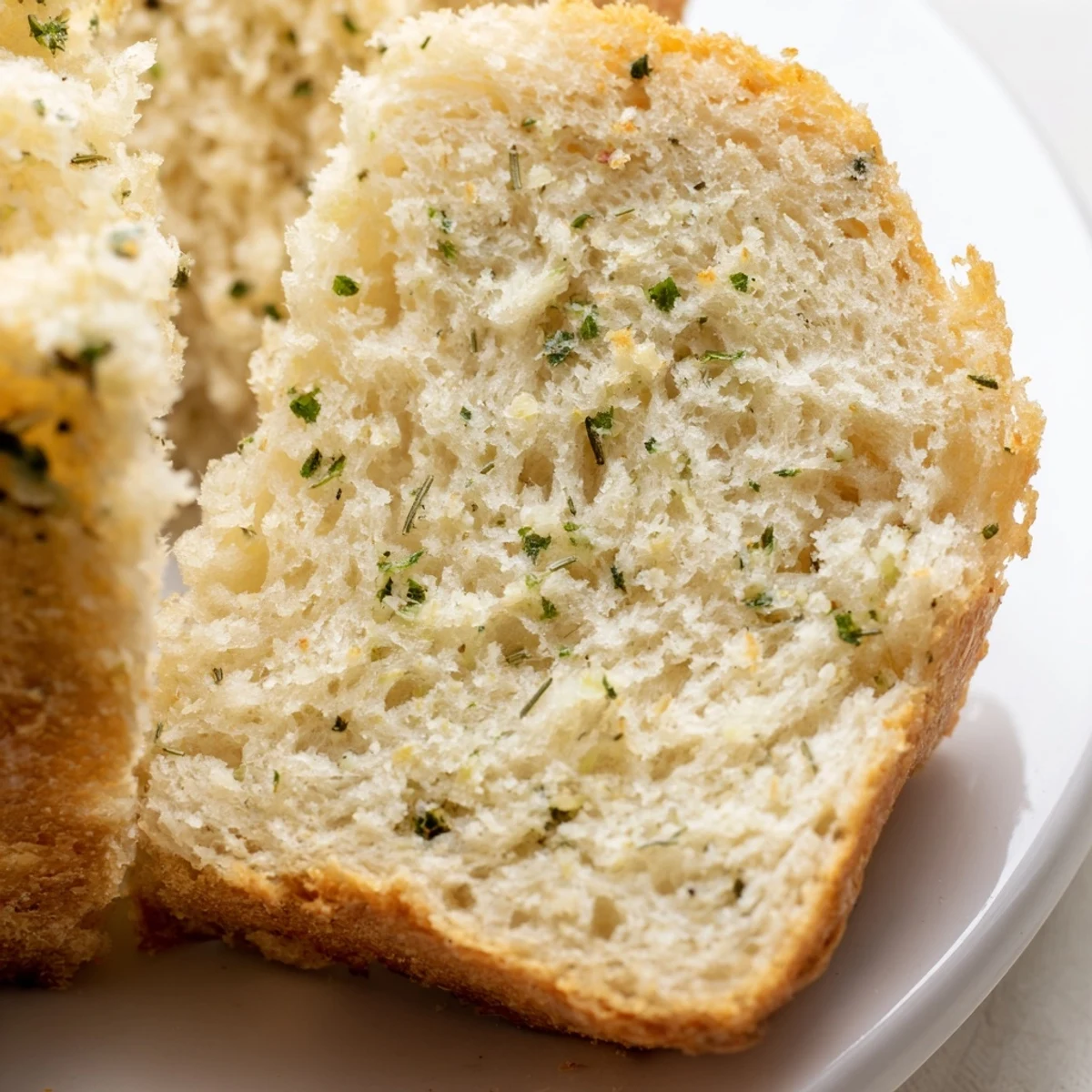Sliced garlic and herb bread loaf garnished with parsley on a wooden cutting board