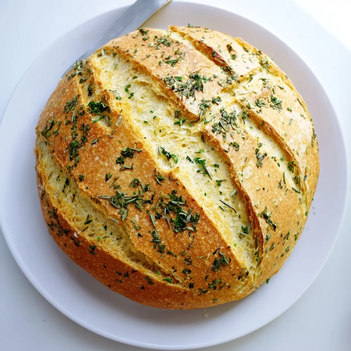 Freshly baked Garlic Herb Dutch Oven Bread with aromatic minced garlic and herbs, displaying a beautifully scored golden crust