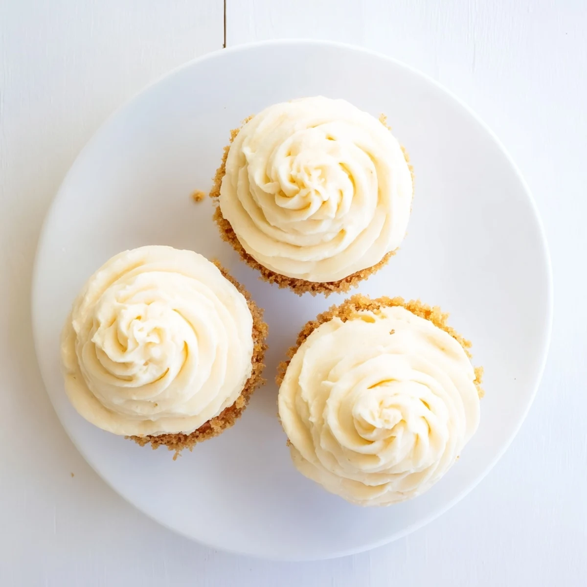 Freshly baked vanilla cupcakes with swirled vanilla buttercream frosting arranged on a decorative serving platter