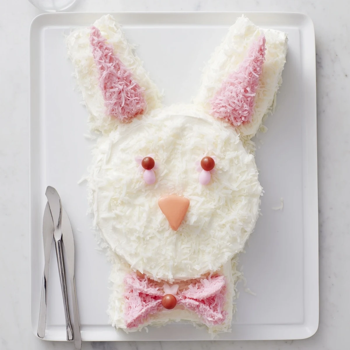 Easter bunny cake with pink fondant ears and coconut fur arranged as festive dessert centerpiece