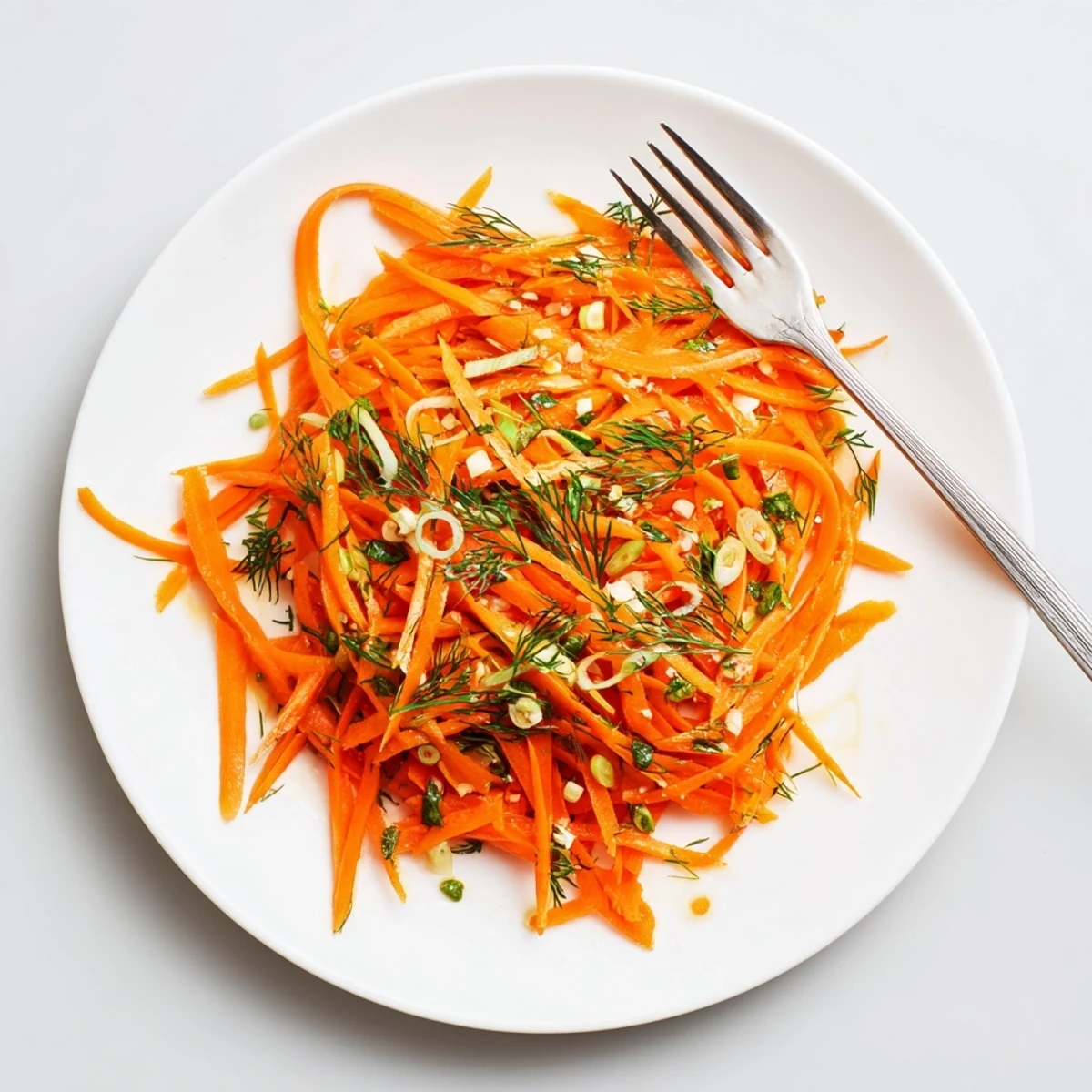 Crisp marinated carrot salad glistening with bright lemon dill dressing in a serving bowl