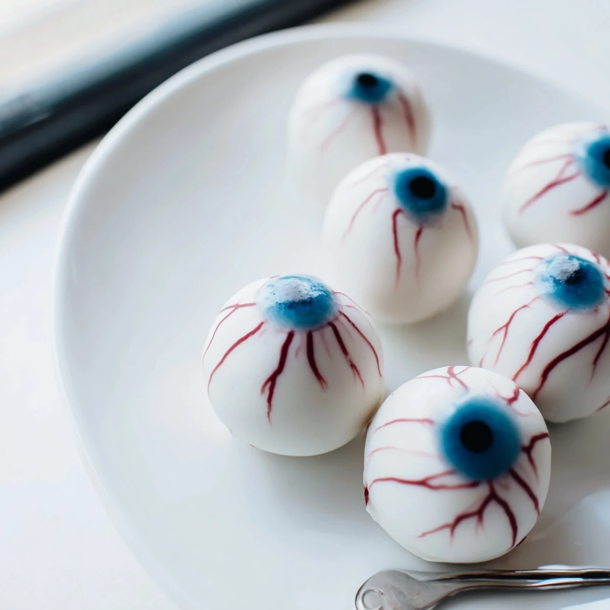Plate of chilling Halloween Cake Eyeballs with gory red veins for a spooky party