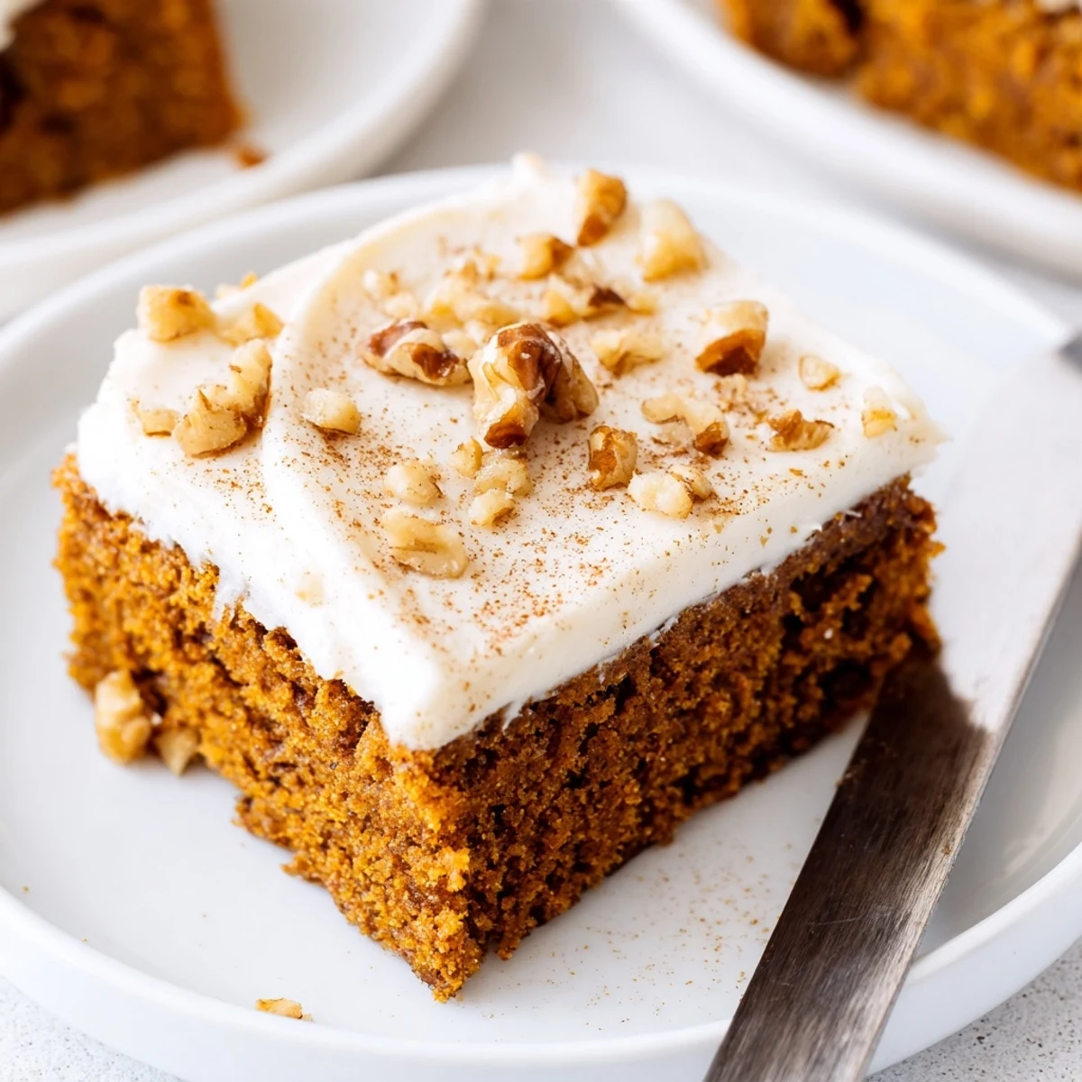 Thick swirls of cream cheese frosting spread over spiced pumpkin bars dusted with cinnamon