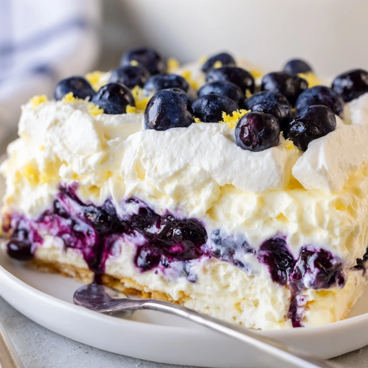 Slice of Lemon Blueberry Lasagna Recipe chilled, topped with whipped cream and zest.