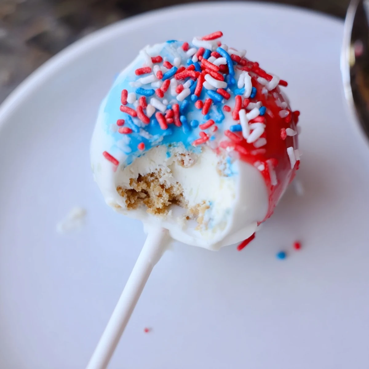 Plate of festive Fourth Of July Star Cheesecake Pops ready for picnic serving.