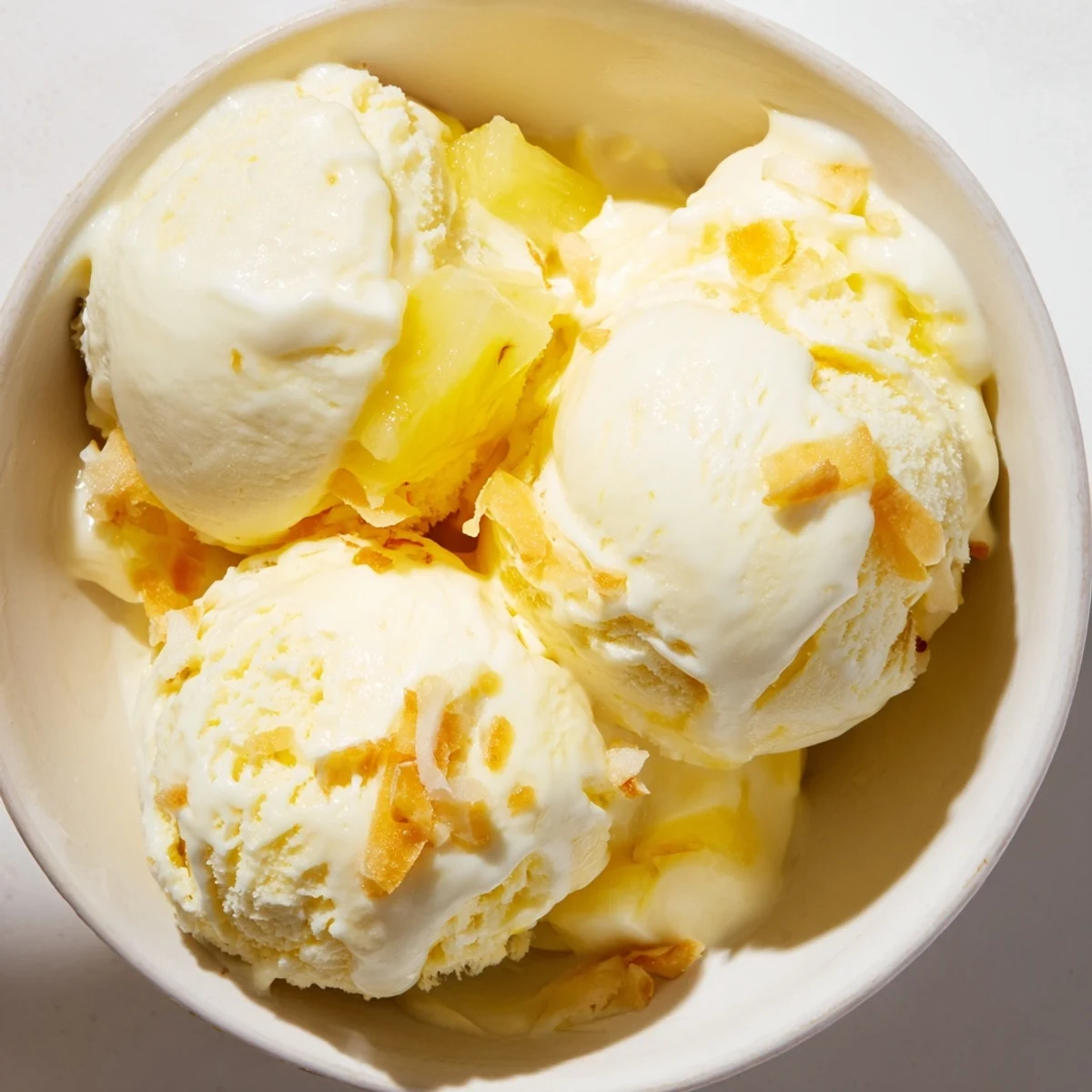 Creamy Pineapple Ice Cream scoops gleaming, silky texture, served with toasted coconut  