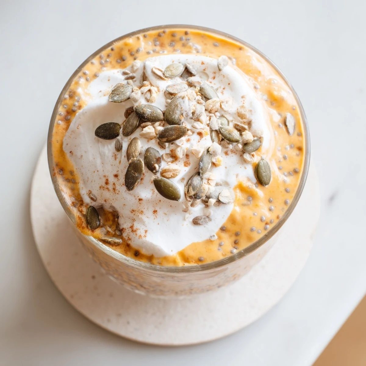 Garnished glass of cool creamy pumpkin chia refreshment with whipped cream and toasted pumpkin seeds on top