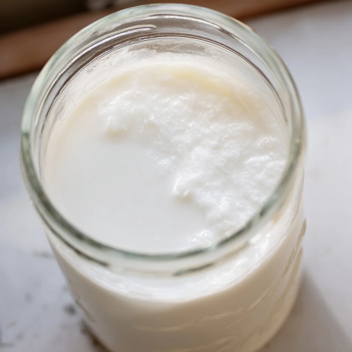 A blender filled with coconut milk being strained through a nut milk bag into a bowl