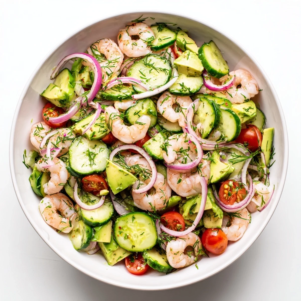 Vibrant cucumber shrimp salad plated with cherry tomatoes avocado red onion and fragrant fresh dill and parsley