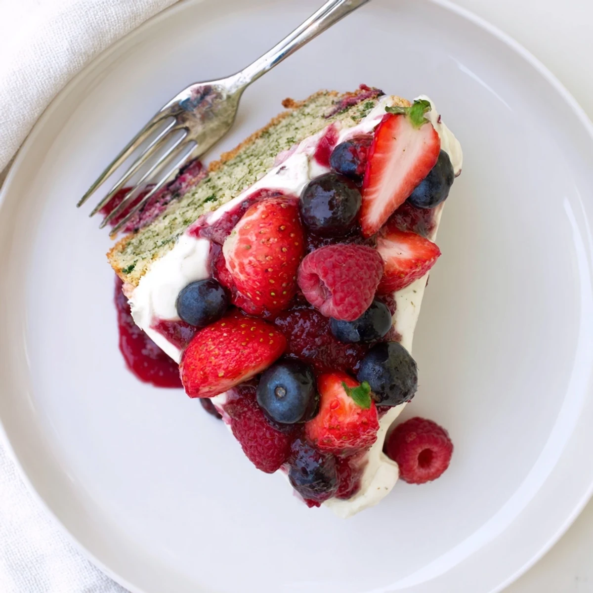 Festive basil berry cake layered with herb-flecked cream and juicy summer berry topping