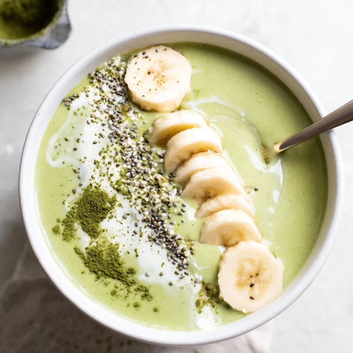 Creamy, vibrant green Matcha Smoothie in glass with banana slice garnish