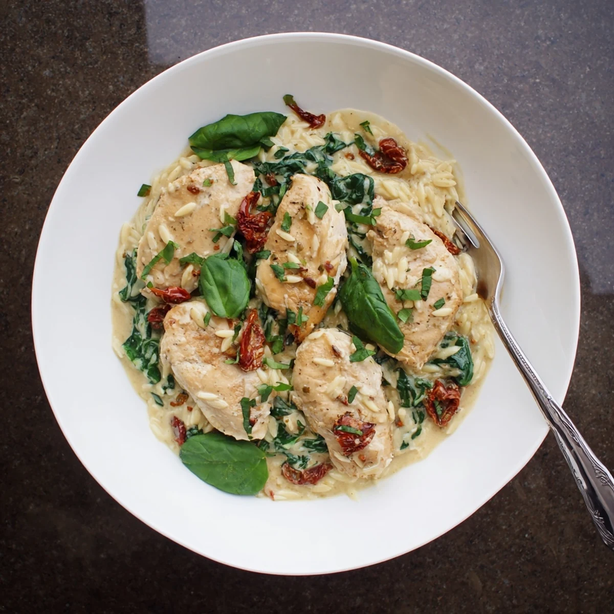 Plated Marry Me Chicken Orzo dish featuring tender chicken pieces in a rich sauce garnished with basil