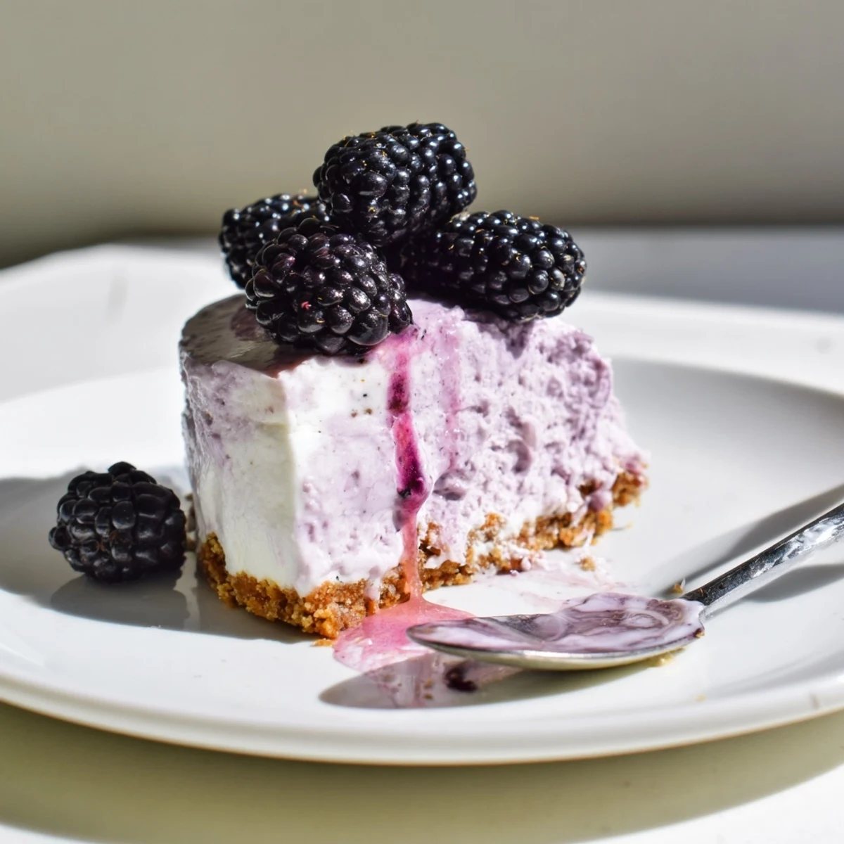 Individual Creamy No Bake Mini Blackberry Lavender Cheesecakes garnished with whole berries on a rustic plate