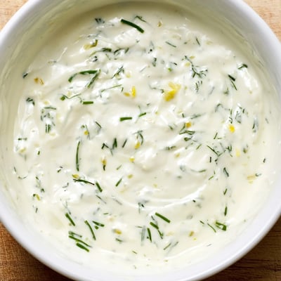 A jar of Creamy Salad Dressing with Herbs next to crisp lettuce and vibrant cherry tomatoes.