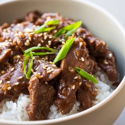 Sizzling beef and onions top a steaming bowl of fluffy rice for this hearty Asian-inspired Beef Bowl meal.