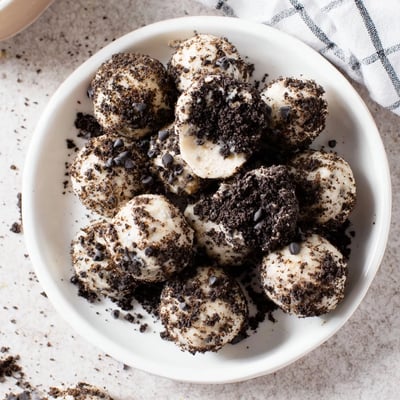 Cream Cheese Oreo Protein Balls drizzled with melted chocolate and served on a tray.